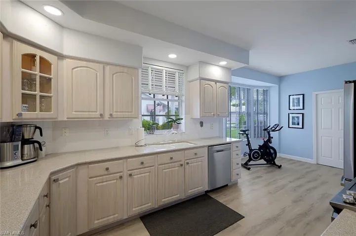 Kitchen with stainless steel dishwasher, backsplash, sink, and light hardwood / wood-style flooring