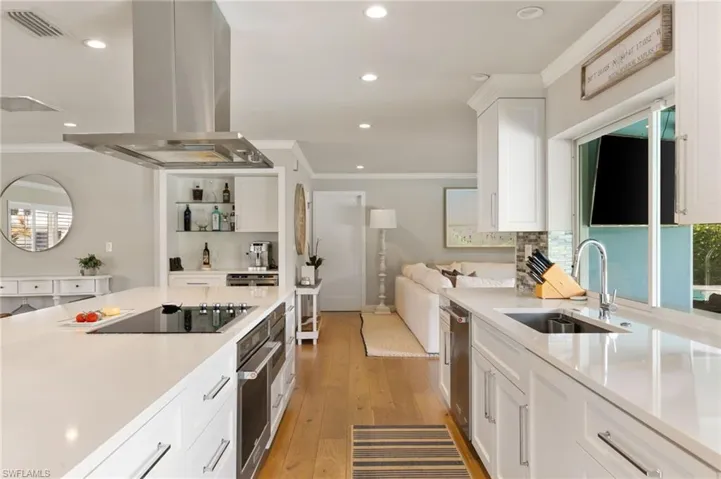 Convenient and central to all, the kitchen offers quartz counters, white shaker cabs and an overlook of the yard and pool