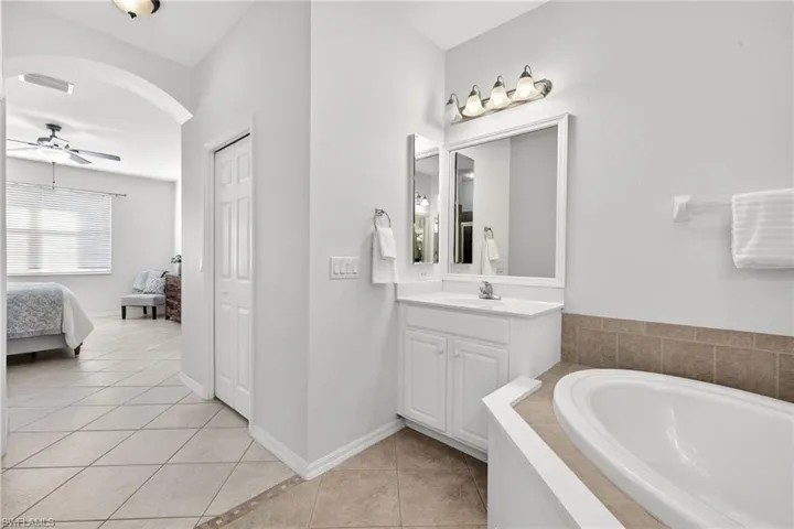 Primary Bathroom with double vanities, soaking tub, light tile patterned floors