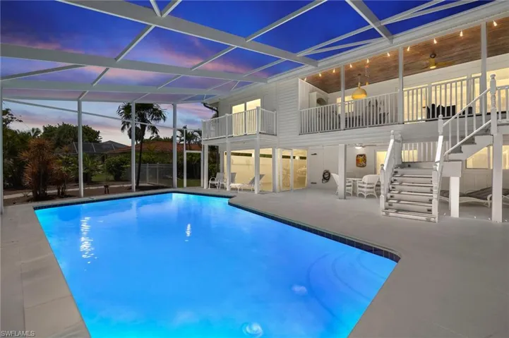 Pool at dusk featuring stairway, a patio, and glass enclosure