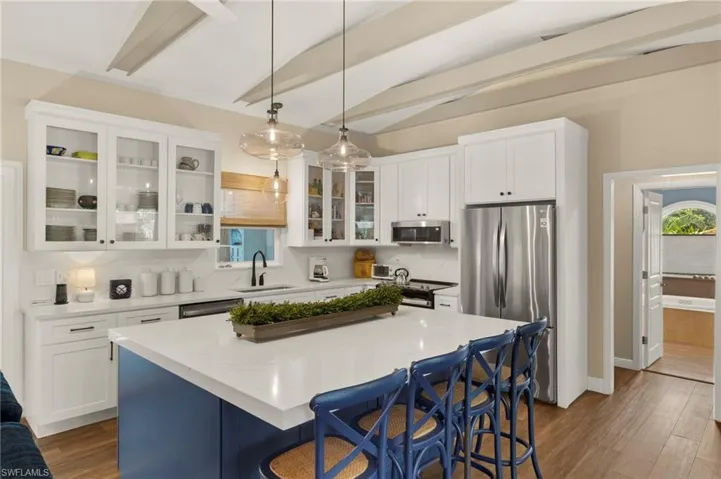 Kitchen with appliances with stainless steel finishes, a breakfast bar, dark wood-type flooring, a center island, and decorative light fixtures