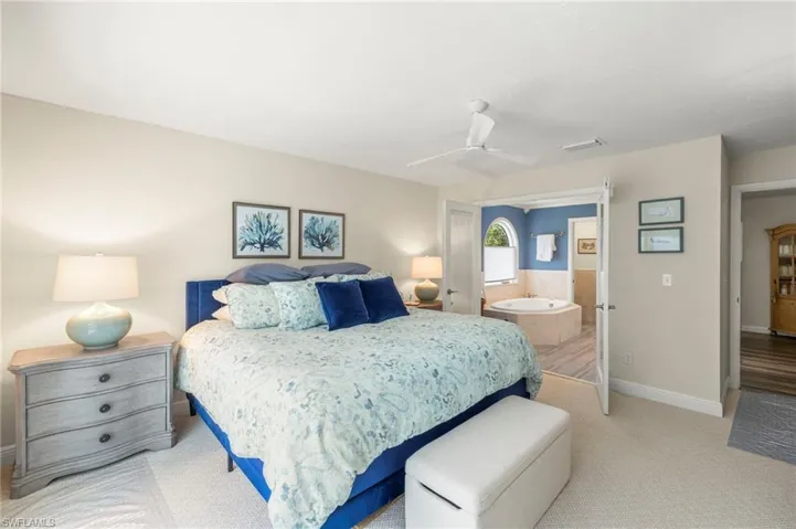 Bedroom featuring light colored carpet, ensuite bathroom, and a ceiling fan