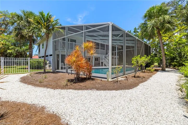 Back of property featuring an outdoor pool, glass enclosure, and a patio