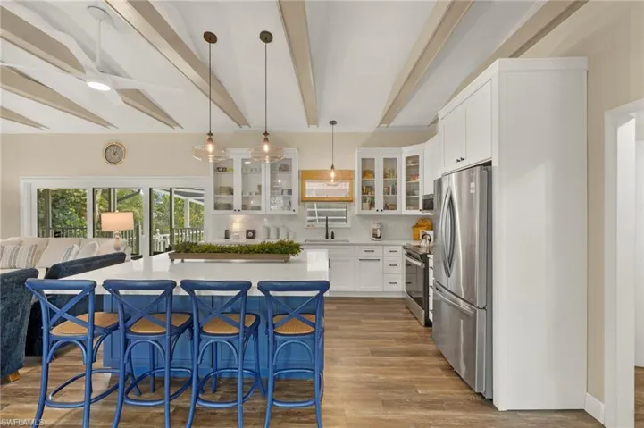 Kitchen featuring appliances with stainless steel finishes, beam ceiling, a breakfast bar, dark wood-style flooring, and a kitchen island