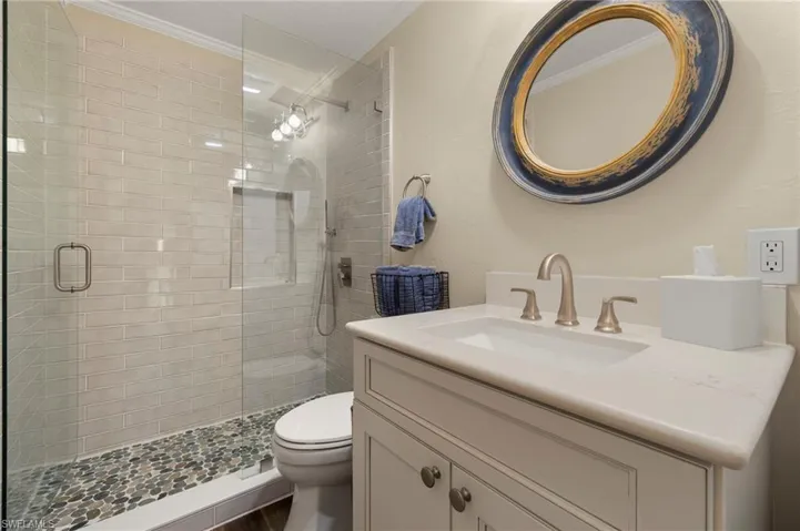 Full bathroom with a stall shower, vanity, crown molding, and wood finished floors
