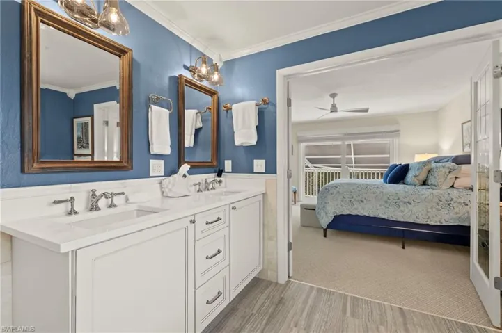 Bathroom featuring connected bathroom, double vanity, crown molding, wood finished floors, and ceiling fan