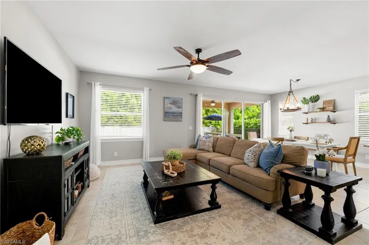 Tiled living room with a healthy amount of sunlight and ceiling fan