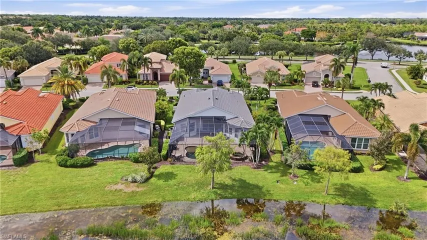 Tile roof residence featuring a screened-in pool, manicured lawn, established landscaping, and a water feature