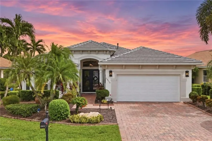 White stucco exterior with a tile roof, double-door entry, and an arched portico