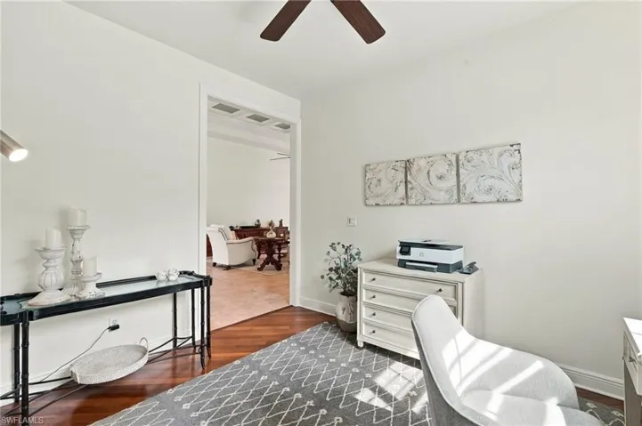 Wood-finish flooring, white painted walls, and a ceiling fan