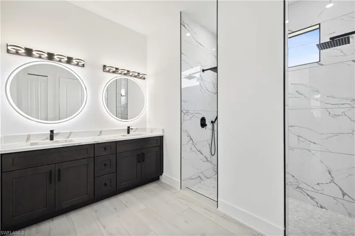 Bathroom featuring a tile shower and dual bowl vanity