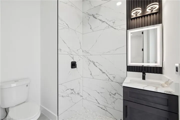 Bathroom with vanity, a tile shower, and toilet