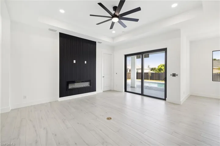 Unfurnished living room featuring light hardwood / wood-style flooring, ceiling fan, and a raised ceiling