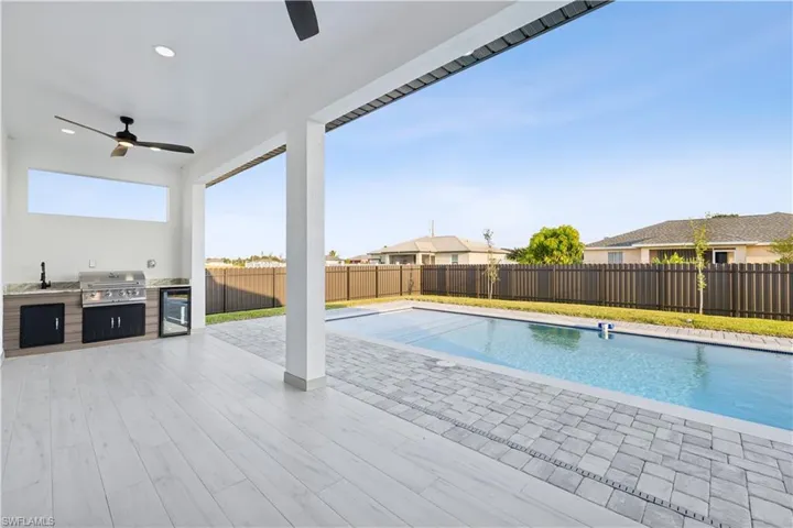 View of swimming pool with ceiling fan, exterior kitchen, a patio area, and a grill