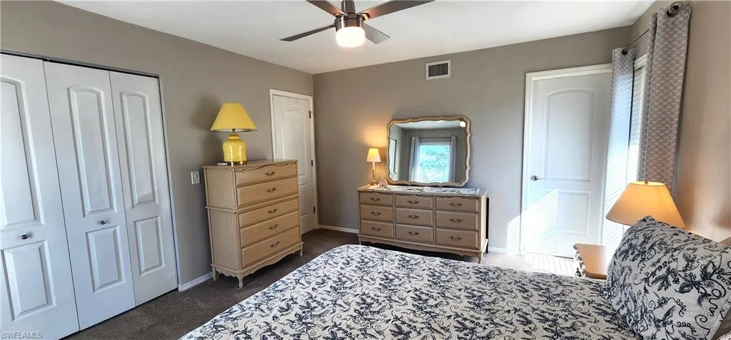 Carpeted bedroom featuring a walk-in closet and ceiling fan