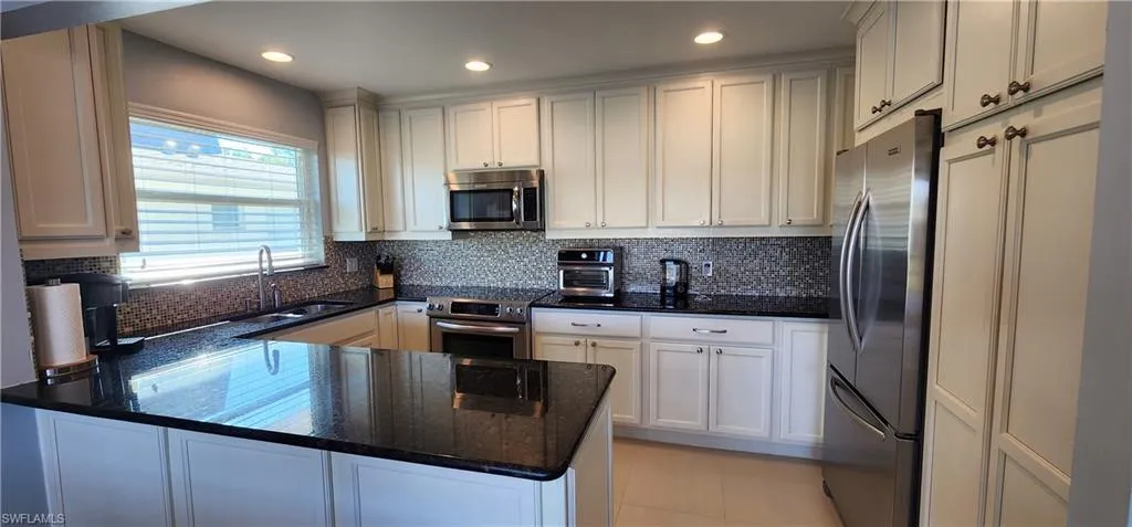 Kitchen with backsplash, white cabinets, countertops. appliances with stainless steel finishes
