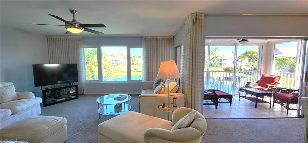 Living room featuring light carpet, ceiling fan, and a healthy amount of sunlight