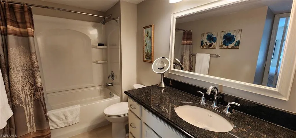 Full bathroom featuring tile patterned flooring, vanity, toilet, and shower / tub combo