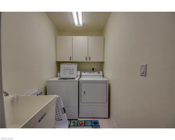 Laundry area featuring cabinets, light tile patterned floors, and separate washer and dryer