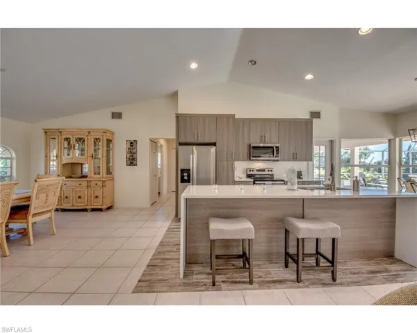 Kitchen with kitchen peninsula, stainless steel appliances, sink, a breakfast bar area, and light tile patterned flooring