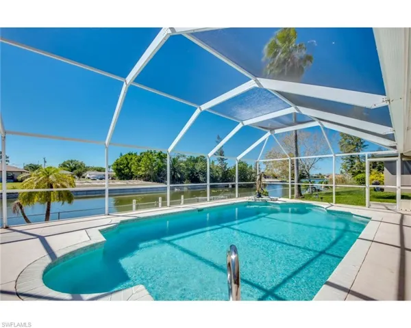 View of pool with a water view, glass enclosure, and a patio area