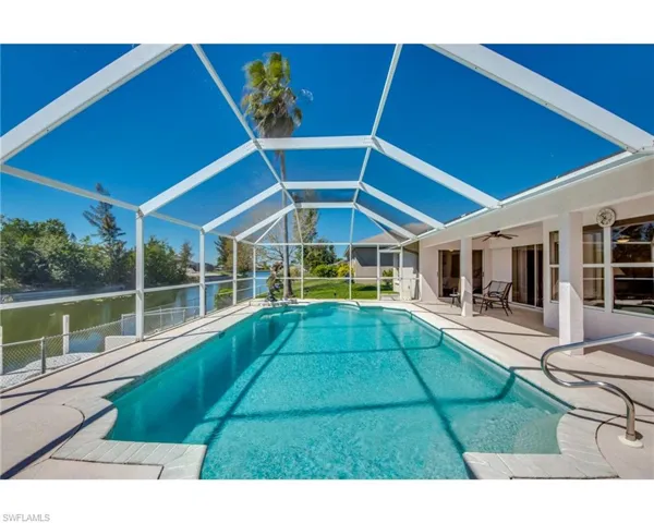View of pool with a water view, a lanai, a patio area, and ceiling fan