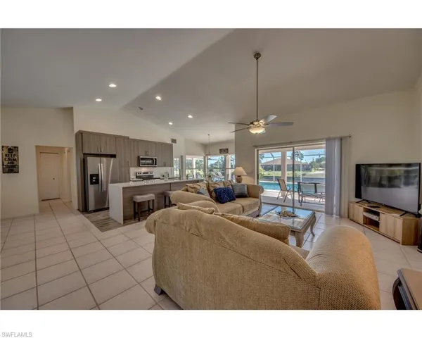 Tiled living room with ceiling fan and high vaulted ceiling