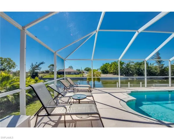 View of swimming pool with glass enclosure, a water view, and a patio