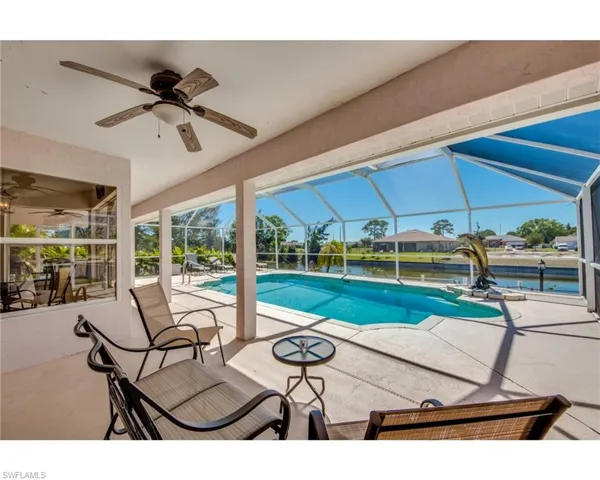 View of swimming pool with glass enclosure, ceiling fan, and a patio area