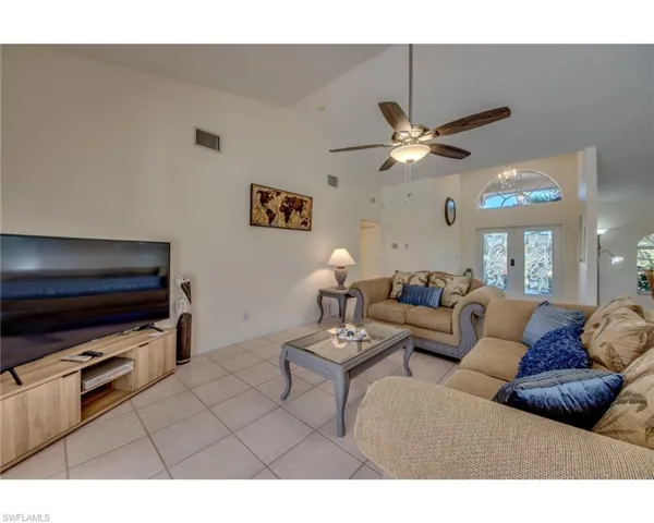Living room with french doors, high vaulted ceiling, ceiling fan, and light tile patterned flooring