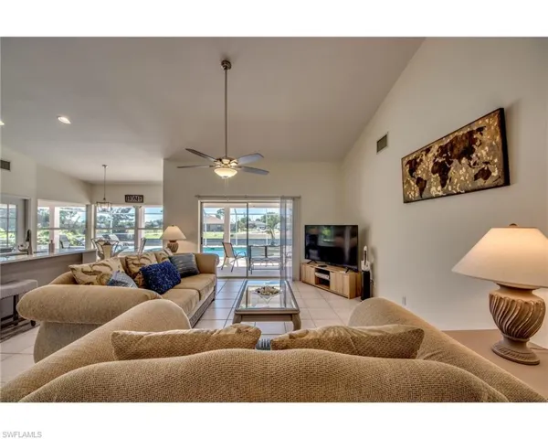 Living room with ceiling fan, light tile patterned flooring, and vaulted ceiling