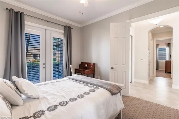Bedroom with ceiling fan, multiple windows, french doors, and light tile floors