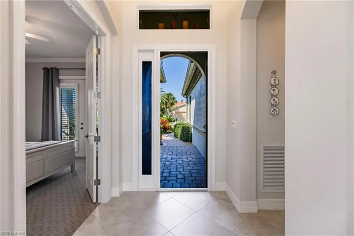 Tiled entrance foyer with a healthy amount of sunlight, ceiling fan, and crown molding