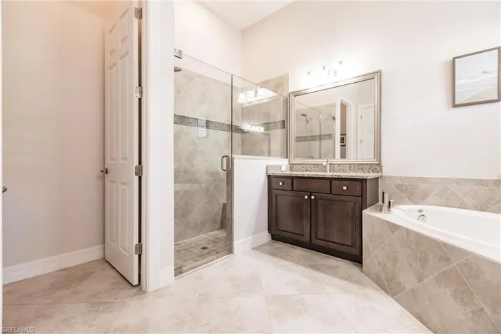 Bathroom featuring tile flooring, vanity, and shower with separate bathtub