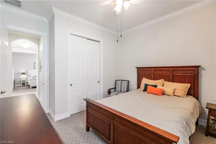 Bedroom featuring ceiling fan, a closet, crown molding, and light carpet