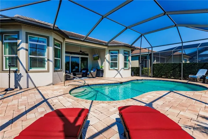 View of pool featuring a patio, glass enclosure, and ceiling fan