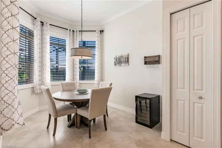 Tiled dining space featuring wine cooler and ornamental molding