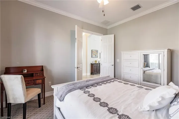Carpeted bedroom with ornamental molding and ceiling fan