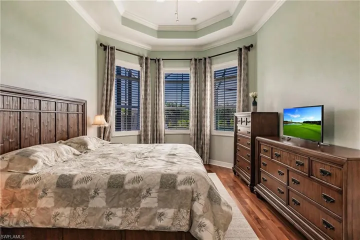 Bedroom featuring wood-type flooring, ornamental molding, and a tray ceiling