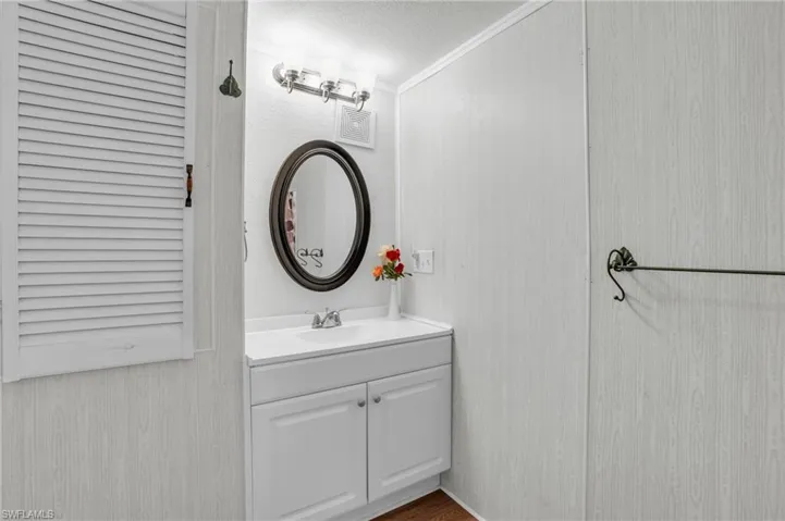 Bathroom with hardwood / wood-style floors, crown molding, a textured ceiling, and vanity
