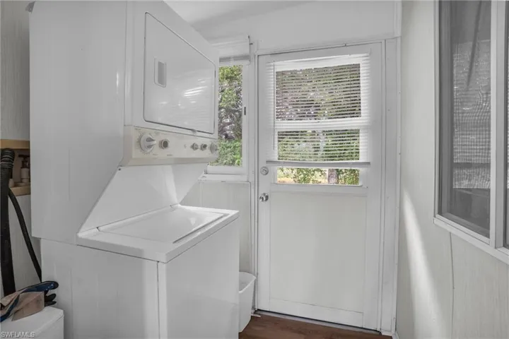 Laundry area featuring stacked washing maching and dryer and dark hardwood / wood-style floors