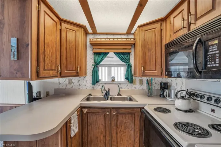 Kitchen with range, sink, a textured ceiling, and kitchen peninsula