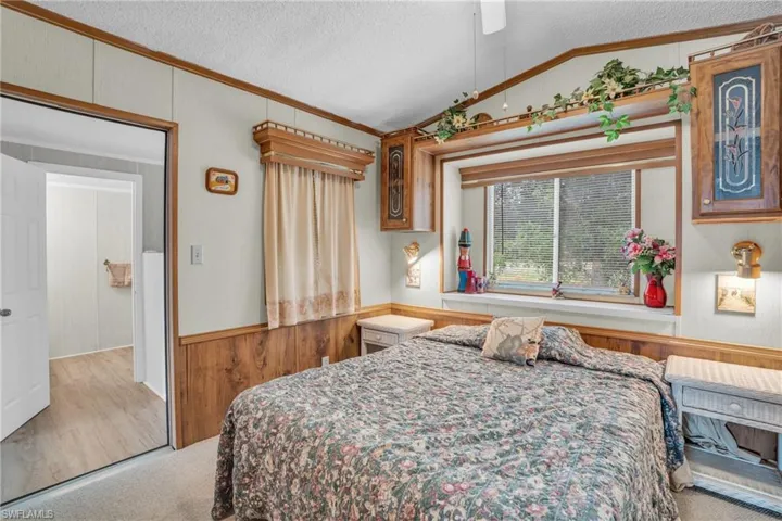 Carpeted bedroom with ceiling fan, vaulted ceiling, and a textured ceiling