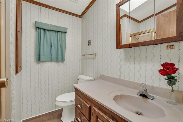 Bathroom with crown molding, a textured ceiling, vanity, and toilet