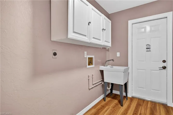 Laundry room featuring cabinet space, hookup for a washing machine, light wood-style floors, and hookup for an electric dryer