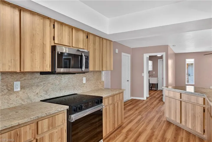 Galley kitchen with brand new stainless/black built in microwave & stove with new granite counters and backsplash