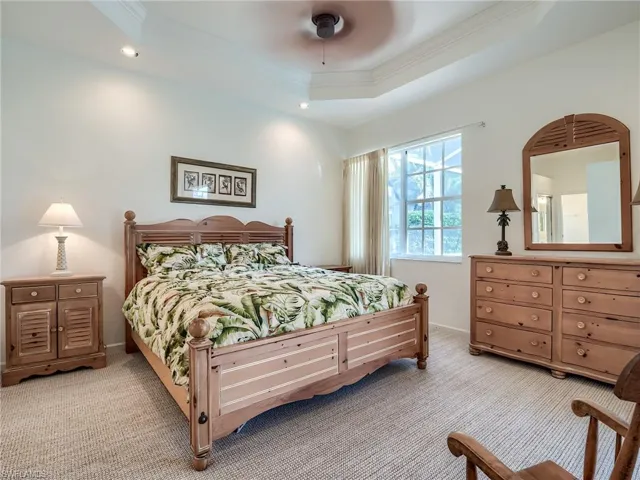 Carpeted bedroom featuring a raised ceiling and ceiling fan