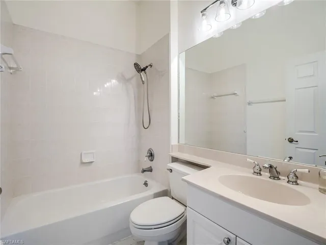 Full bathroom with vanity, tiled shower / bath combo, and toilet