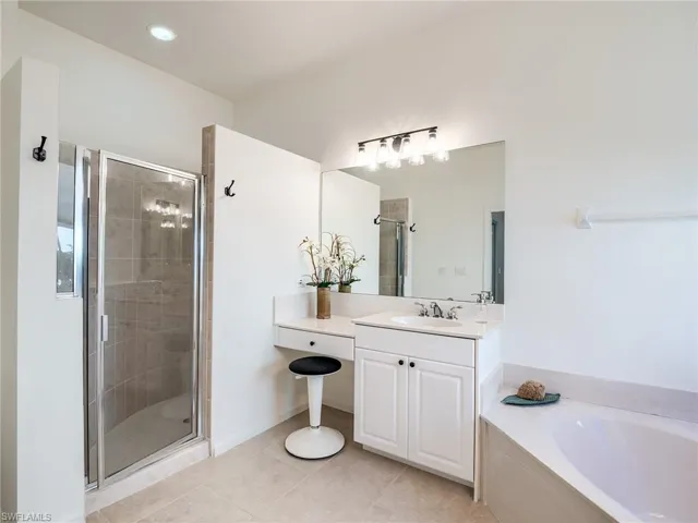 Bathroom featuring shower with separate bathtub, tile patterned floors, and vanity