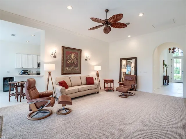 lCarpeted iving room with crown molding and ceiling fan